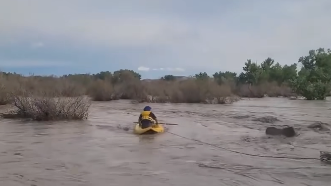 First responders and civilians work to rescue a man stranded in rushing water in Green River, Utah on Saturday, Sept. 13, 2025.